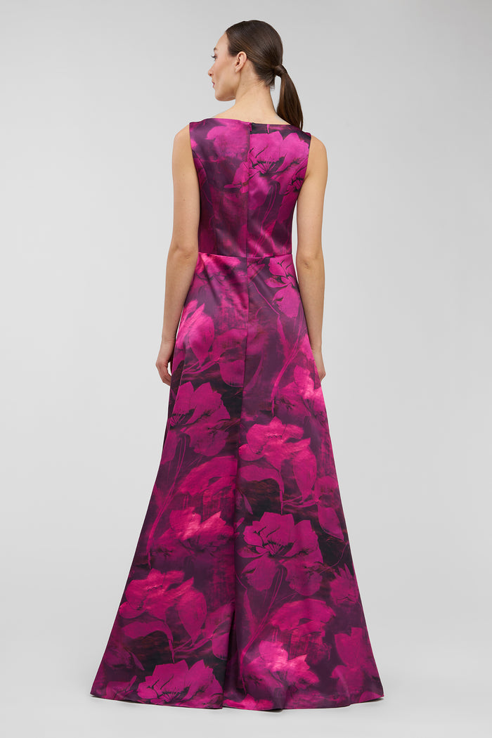 Woman wearing a vibrant pink and purple floral dress on a light gray background