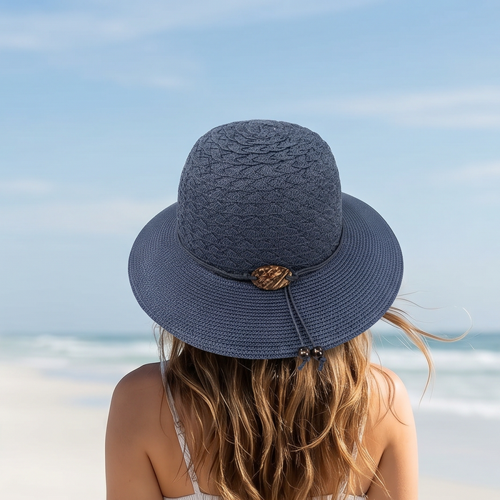 Woman wearing a blue sun hat and white dress on a beach
