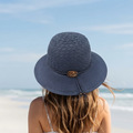 Woman wearing a blue sun hat and white dress on a beach