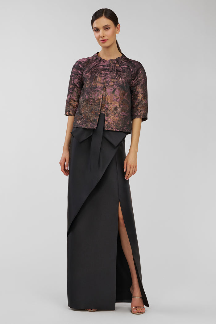 Woman wearing a patterned top and black skirt on a white background